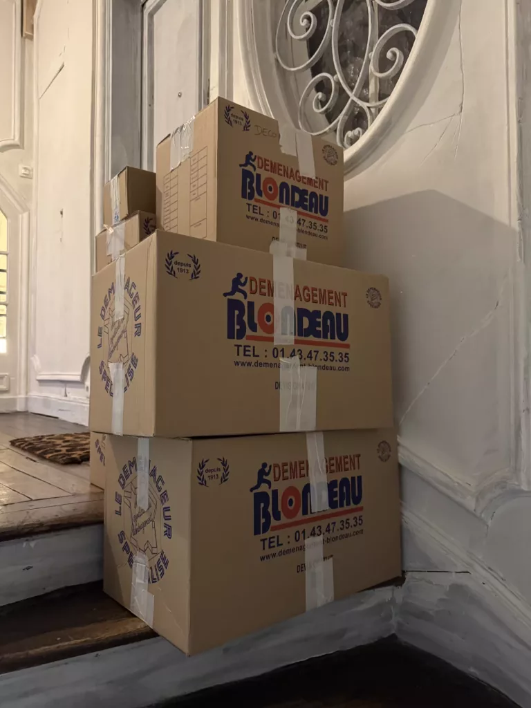 Déménageurs portant masques et gants, utilisant du gel hydroalcoolique et respectant la distanciation sanitaire lors d’un déménagement en période de confinement.