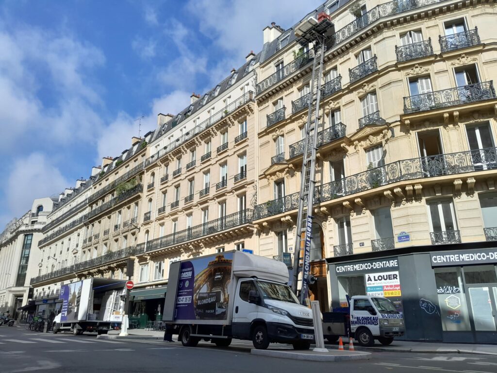 Camion de déménagement Déménagement Blondeau stationné devant un immeuble parisien